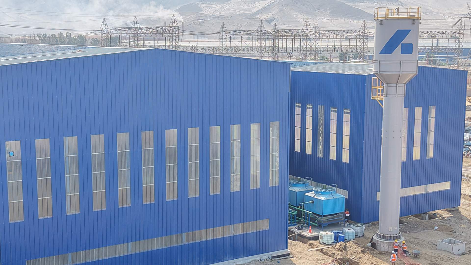 Exterior shot of Bradken's foundry in Chilca Peru ahead of it's opening in July 2026. Two large blue buildings stand against a mountain background.